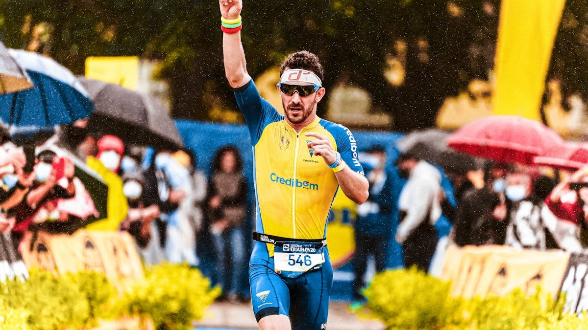 A triumphant marathon runner raising his arm in victory during a rainy sports event.